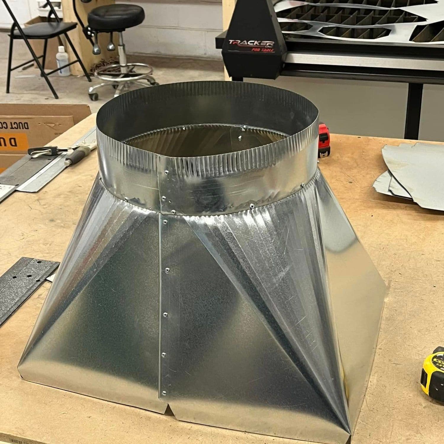 A custom galvanized fitting with a round collar on a square base