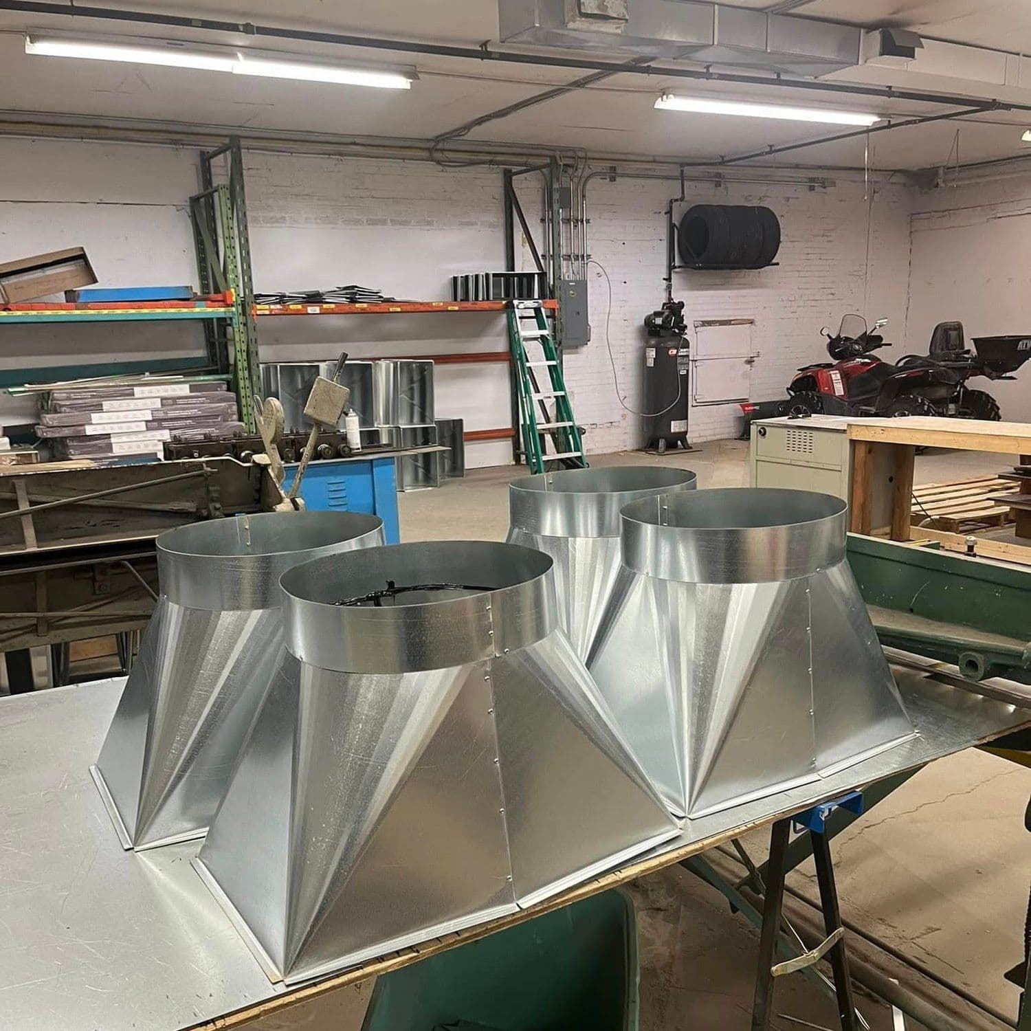 Two galvanized square-to-round duct transitions side by side on the bench